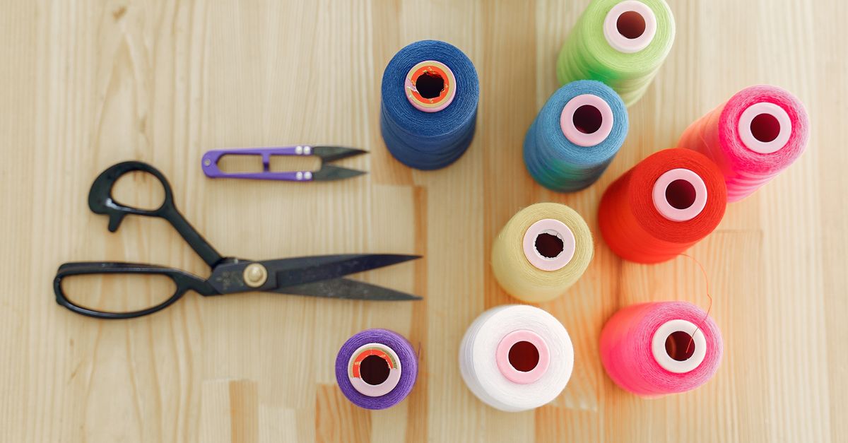 Mesa de taller con materiales de manualidades, tijeras y personas trabajando alrededor